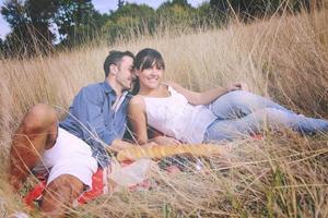 pareja feliz disfrutando de un picnic en el campo en hierba larga foto