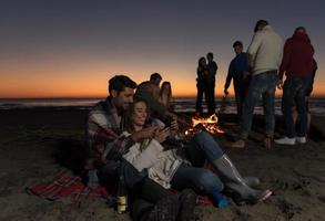 Couple enjoying bonfire with friends on beach photo