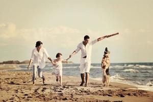 familia feliz jugando con el perro en la playa foto