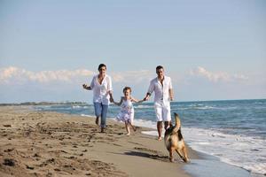 happy family playing with dog on beach photo