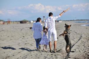 happy family playing with dog on beach photo