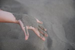 arena fina goteando a través de manos de mujer foto