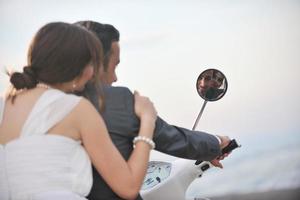 just married couple on the beach ride white scooter photo