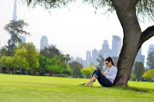 Beautiful young woman with  tablet in park photo