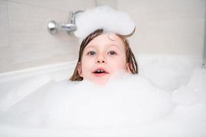 little girl in bath playing with foam photo