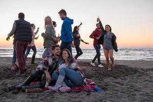 Couple enjoying with friends at sunset on the beach photo