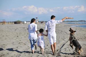 happy family playing with dog on beach photo