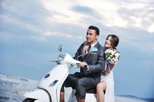 just married couple on the beach ride white scooter photo