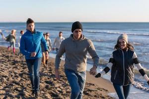 grupo de amigos corriendo en la playa durante el día de otoño foto