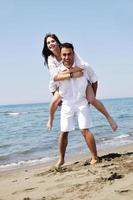 feliz pareja joven divertirse en la playa foto