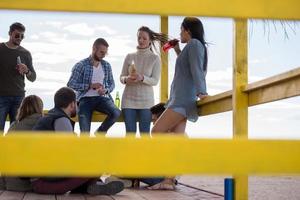 grupo de amigos divirtiéndose el día de otoño en la playa foto