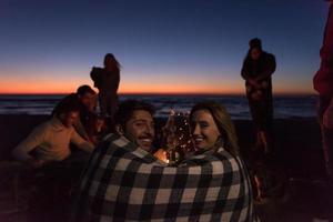 Couple enjoying with friends at sunset on the beach photo