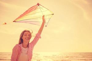 mujer joven con cometa en la playa el día de otoño foto