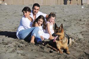 familia feliz jugando con el perro en la playa foto