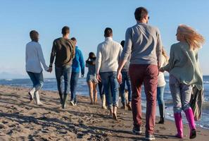 Group of friends running on beach during autumn day photo