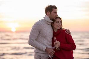 Couple hugging and drinking beer together at the beach photo