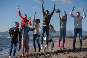 young friends jumping together at autumn beach photo