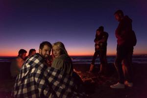 pareja disfrutando con amigos al atardecer en la playa foto