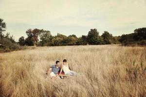 happy couple enjoying countryside picnic in long grass photo