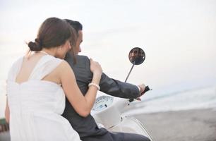 just married couple on the beach ride white scooter photo