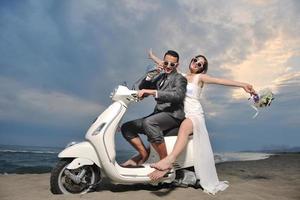 just married couple on the beach ride white scooter photo