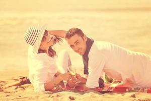 pareja joven disfrutando de un picnic en la playa foto