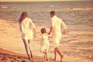 familia joven feliz divertirse en la playa foto