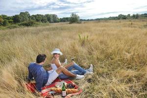 pareja feliz disfrutando de un picnic en el campo en hierba larga foto