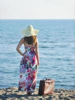 mujer con maleta en la playa foto