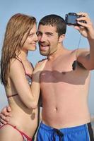 feliz pareja joven enamorada tomando fotos en la playa
