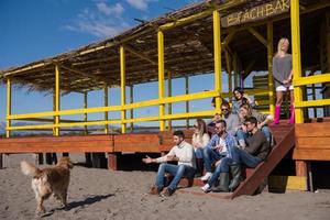 Group of friends having fun on autumn day at beach photo