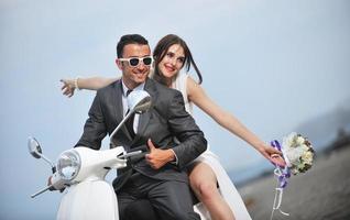 just married couple on the beach ride white scooter photo