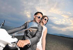 just married couple on the beach ride white scooter photo