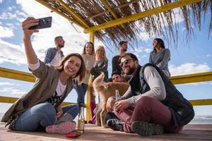 grupo de amigos divirtiéndose el día de otoño en la playa foto