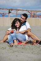 pareja joven disfrutando de un picnic en la playa foto