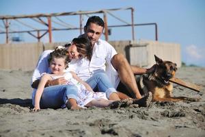 familia feliz jugando con el perro en la playa foto