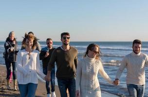 Group of friends running on beach during autumn day photo