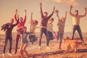 young friends jumping together at autumn beach photo