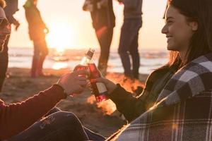 Couple enjoying with friends at sunset on the beach photo