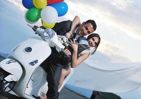 just married couple on the beach ride white scooter photo