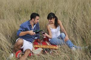 happy couple enjoying countryside picnic in long grass photo