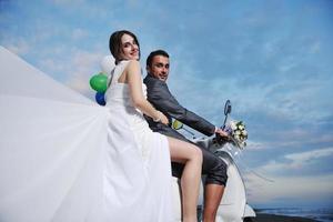 just married couple on the beach ride white scooter photo