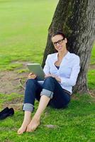 Beautiful young woman with  tablet in park photo