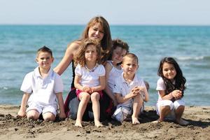 retrato de grupo de niños con profesor en la playa foto