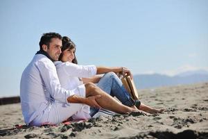 pareja joven disfrutando de un picnic en la playa foto