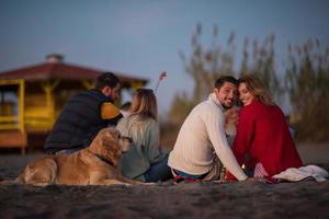 Couple enjoying with friends at sunset on the beach photo