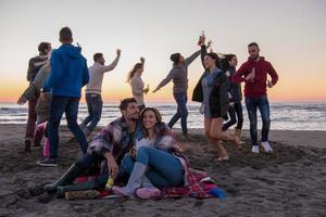 Couple enjoying with friends at sunset on the beach photo