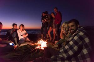Couple enjoying with friends at sunset on the beach photo