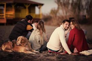 pareja disfrutando con amigos al atardecer en la playa foto