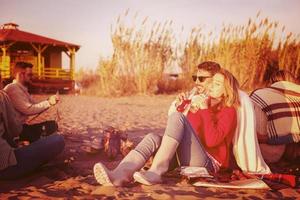 Couple enjoying with friends at sunset on the beach photo